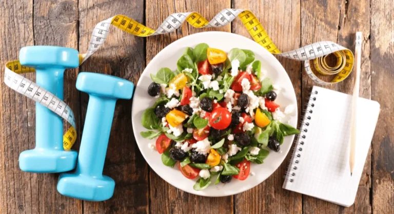 Ensalada saludable con verduras frescas, pesas y cinta métrica, representando un estilo de vida equilibrado con nutrición y ejercicio en Centro Fisiobrain Azuqueca de Henares.