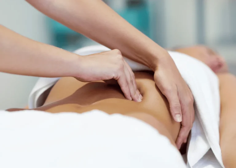 Fisioterapeuta realizando terapia manual sobre el abdomen de una paciente